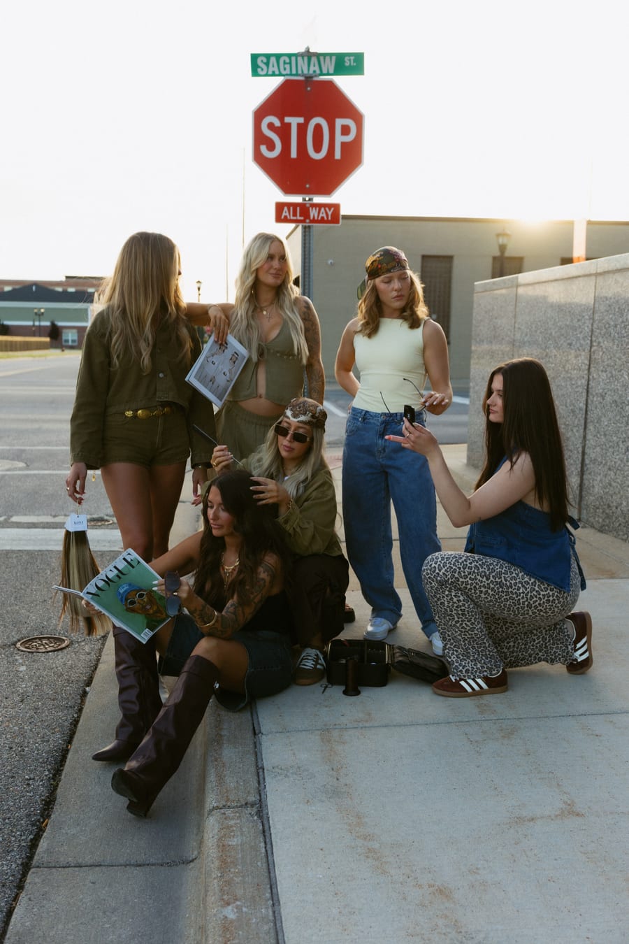The Artistry Lounge team posing beneath the Saginaw Street sign in Bay City